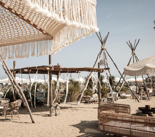 Spiaggia boho con arredi in vimini e decorazioni in macramè.