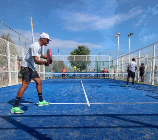 Giocatori di padel su un campo blu all'aperto.