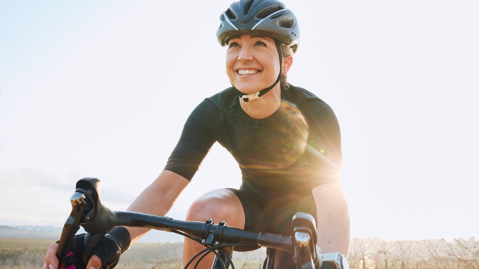 Ciclista sorridente in abbigliamento sportivo, pedalando sotto il sole.