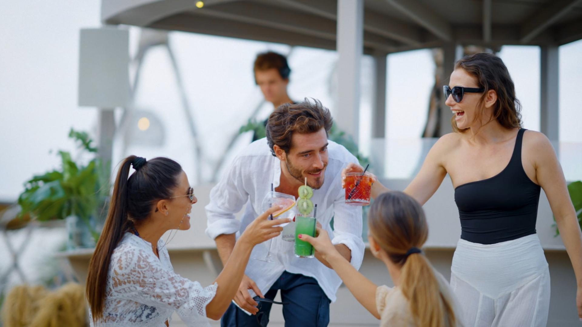 Gruppo di amici brinda con cocktail in un ambiente estivo e rilassato.