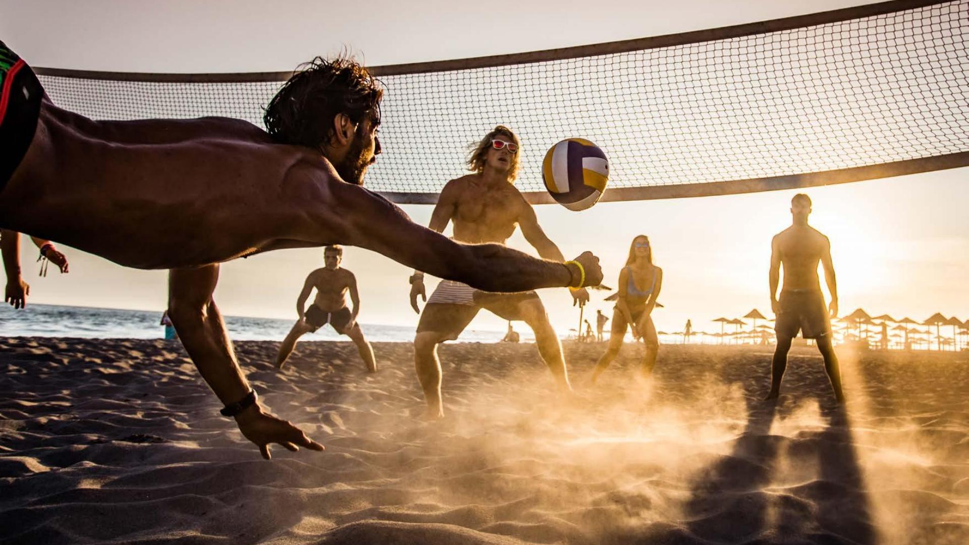 Giocatori di beach volley al tramonto, azione intensa sulla sabbia.