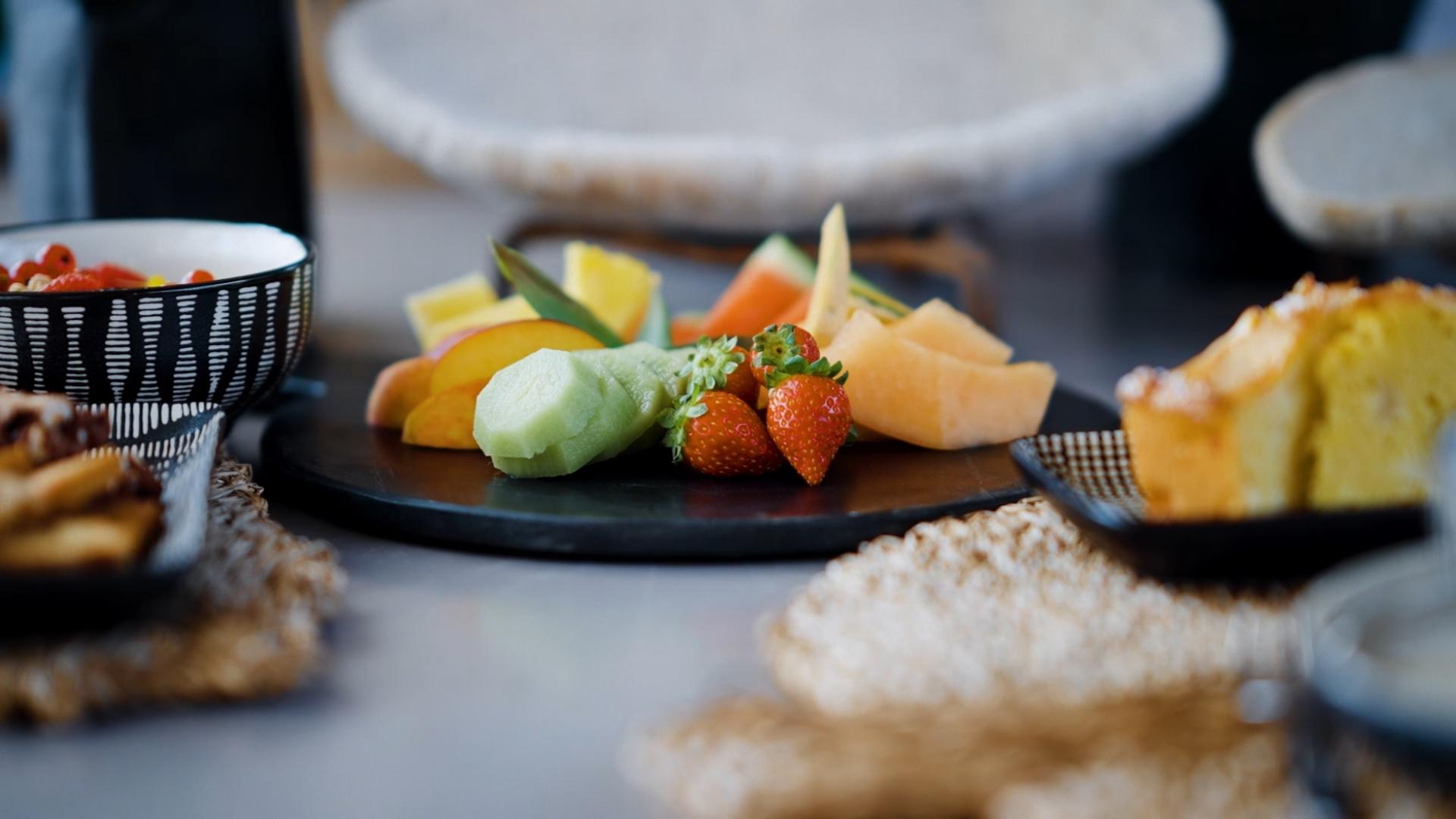 Piatto di frutta fresca con fragole, melone e fette di torta.