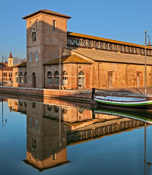 Edificio storico in mattoni riflesso nel canale con barca ormeggiata.