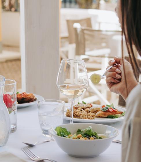 Pranzo elegante con risotto, insalata e vino bianco in un ristorante luminoso.