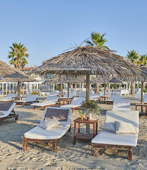 Spiaggia con lettini e ombrelloni di paglia, atmosfera estiva e rilassante.