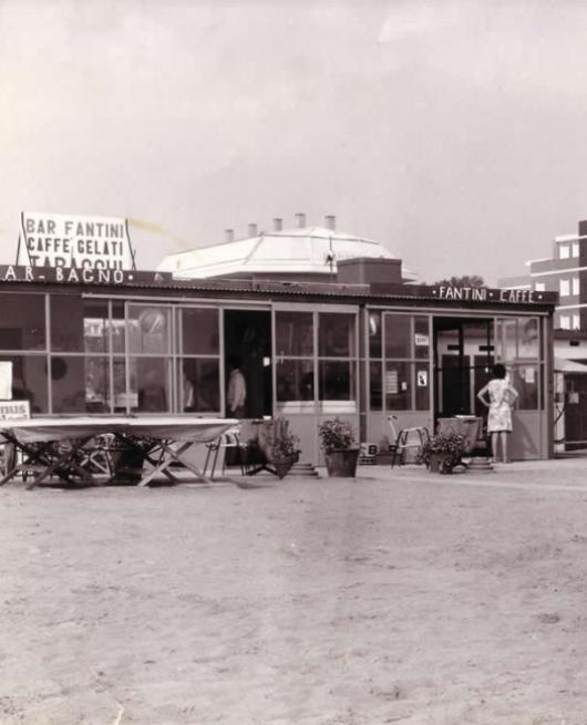 Bar sulla spiaggia con tavolini, insegna 'Bar Fantini Caffè Gelati'.