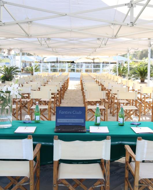 Conferenza sulla spiaggia con sedie e tavoli sotto un gazebo al Fantini Club.