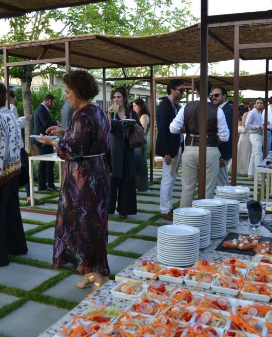 Evento all'aperto con buffet, persone eleganti e piatti di antipasti vari.