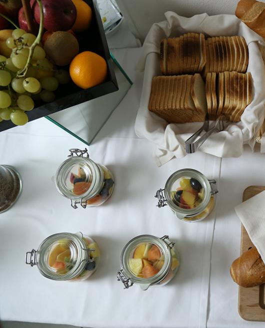 Buffet con frutta, pane assortito e vasetti di macedonia.