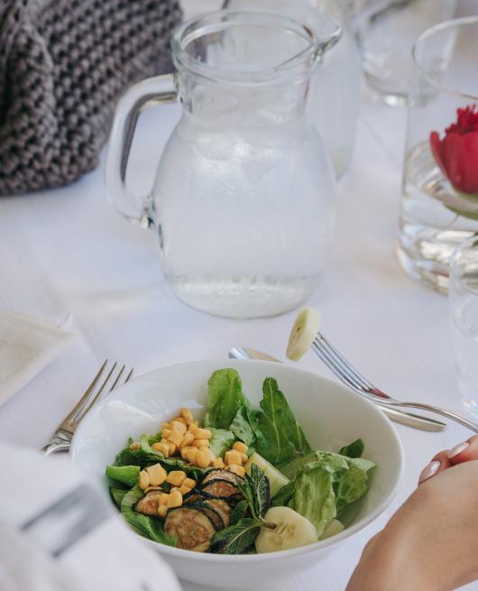 Insalata fresca con lattuga, mais, zucchine e cetriolo, servita con acqua ghiacciata.