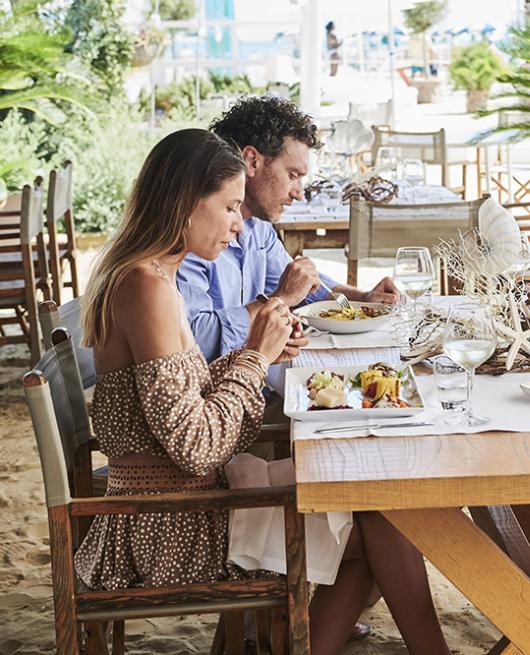 Tre persone pranzano all'aperto in un ristorante sulla spiaggia.