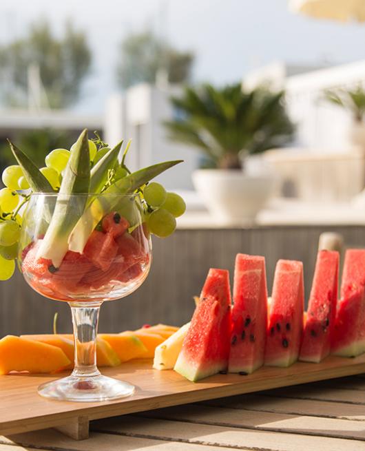 Frutta estiva su un vassoio: anguria, melone, uva e ananas in coppa.