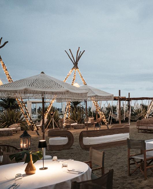 Ristorante all'aperto sulla spiaggia con decorazioni luminose e atmosfera accogliente.