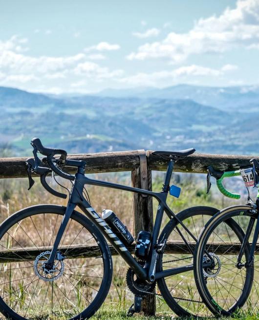 Due biciclette da corsa appoggiate a una staccionata con vista panoramica sulle colline.