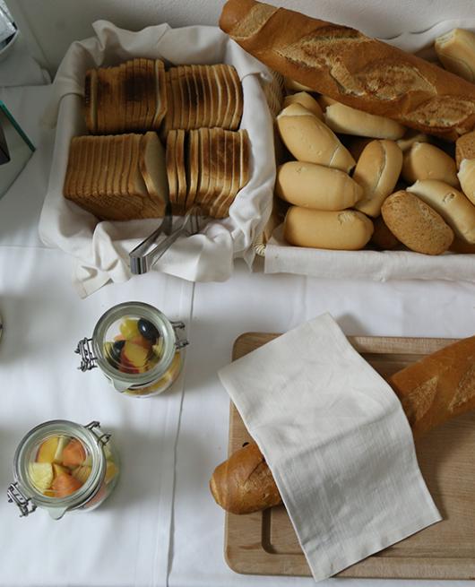 Buffet con pane, frutta fresca e barattoli di macedonia.