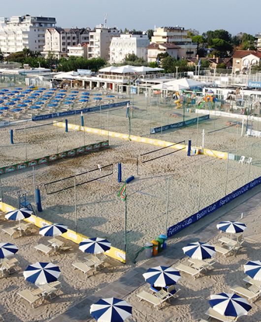 Spiaggia attrezzata con ombrelloni, lettini e campi da beach volley.