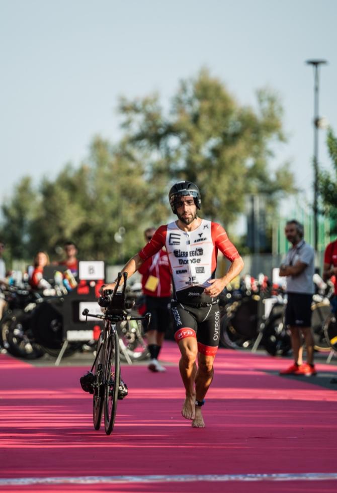 Atleta in transizione triathlon, corre a piedi nudi con la bici.