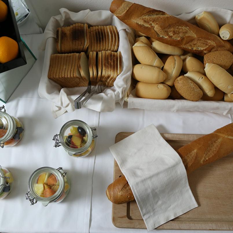 Buffet con frutta, pane assortito e vasetti di macedonia.